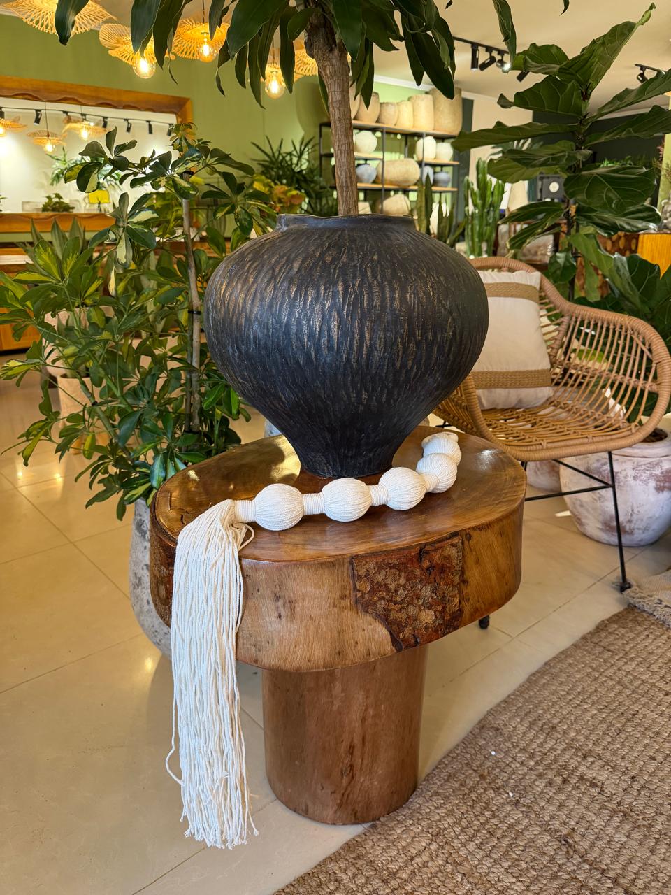 Pote preto esculpido sobre mesa-tronco